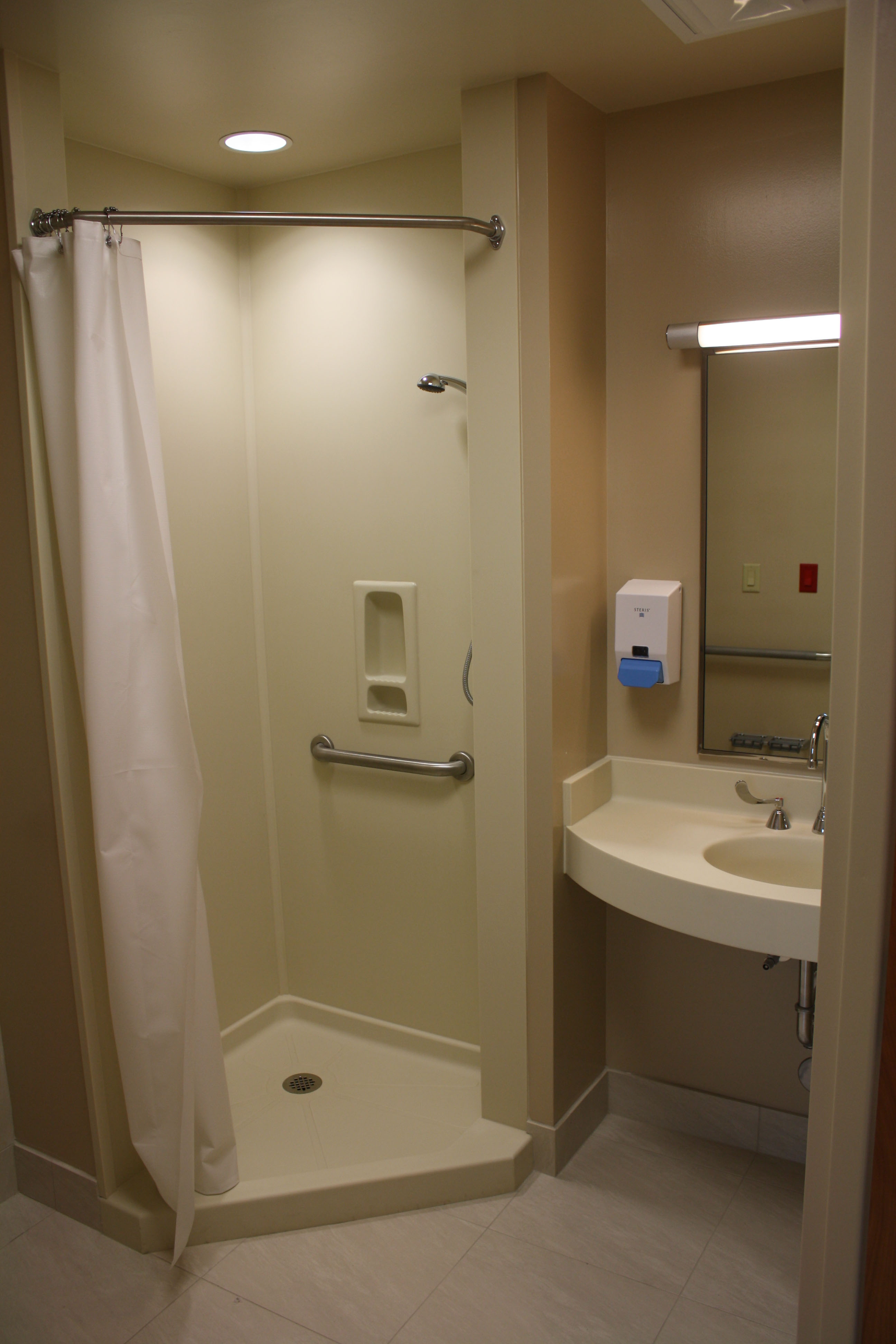 Avonite Surfaces® Bone 8010 shower wet wall panels in a hospital bathroom.