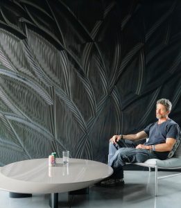 Mario Romano enjoys one of his sculptured walls made of Corian® Solid Surface